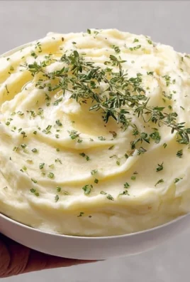 Creamy garlic mashed potatoes in a bowl, garnished with herbs.