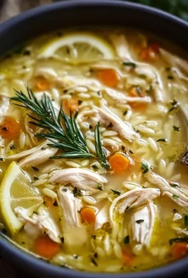 Bowl of Greek Lemon Chicken Soup garnished with fresh herbs and lemon slices.