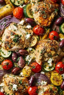Greek sheet pan chicken with vegetables and herbs on a baking tray