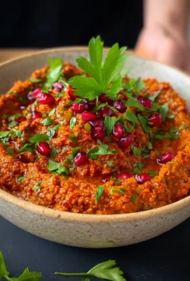 Bowl of creamy muhammara dip served with pita bread and vegetables