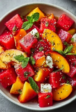 Peach and watermelon summer salad served in a bowl, garnished with fresh mint.