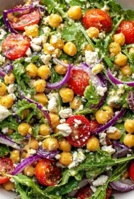 Chickpea Arugula Salad topped with Lemon Dijon Dressing on a white plate.