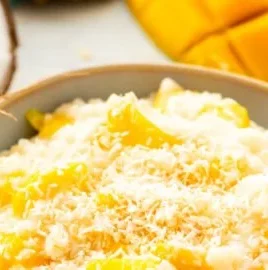 Coconut Mango Rice Pudding topped with fresh mango slices and toasted coconut.