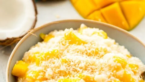Coconut Mango Rice Pudding topped with fresh mango slices and toasted coconut.