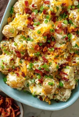 Creamy loaded potato salad bowl garnished with fresh herbs.