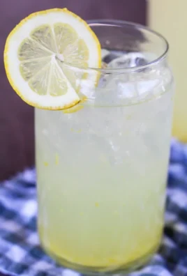 Glass of refreshing homemade lemonade with lemon slices and mint leaves