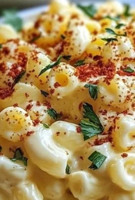 A bowl of Deviled Egg Macaroni Salad garnished with paprika and herbs