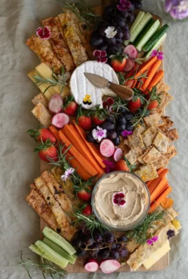 A plate of colorful edible flower crackers garnished with fresh herbs