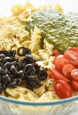 Bowl of incredibly easy pesto pasta salad with cherry tomatoes and basil