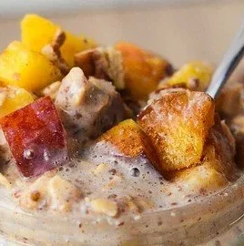 Bowl of peach cobbler overnight oats with fresh peaches and granola