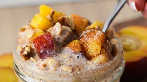 Bowl of peach cobbler overnight oats with fresh peaches and granola