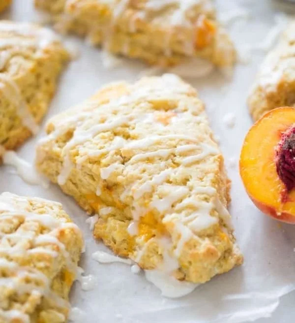 Freshly baked peach scones with chunks of peaches on a cooling rack