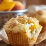 Freshly baked Peaches and Cream Muffins with juicy peach slices and creamy topping