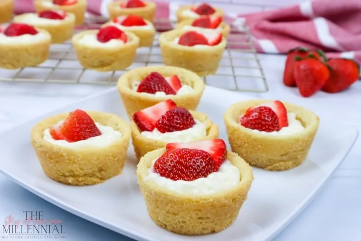 Strawberry cheesecake cookie cups topped with fresh strawberries and cream