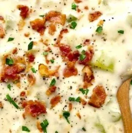 Bowl of creamy clam chowder garnished with herbs and served with crackers
