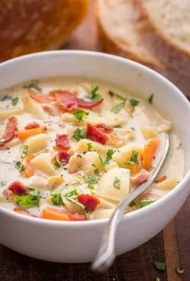 Delicious bowl of creamy clam chowder garnished with herbs and crackers