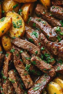 Garlic butter steak bites with crispy potatoes in a skillet