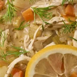 Bowl of Greek lemon chicken soup with herbs and lemon slices