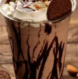 Oreo iced coffee in a clear glass with whipped cream and crushed Oreos on top