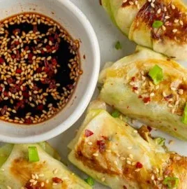Plate of vegan cabbage-wrapped dumplings filled with tofu and herbs