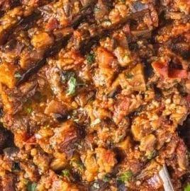 A bowl of Zaalouk, a Moroccan eggplant dip garnished with herbs.