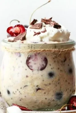 Cherry Chocolate Chunk Protein Overnight Oats in a jar topped with fresh cherries