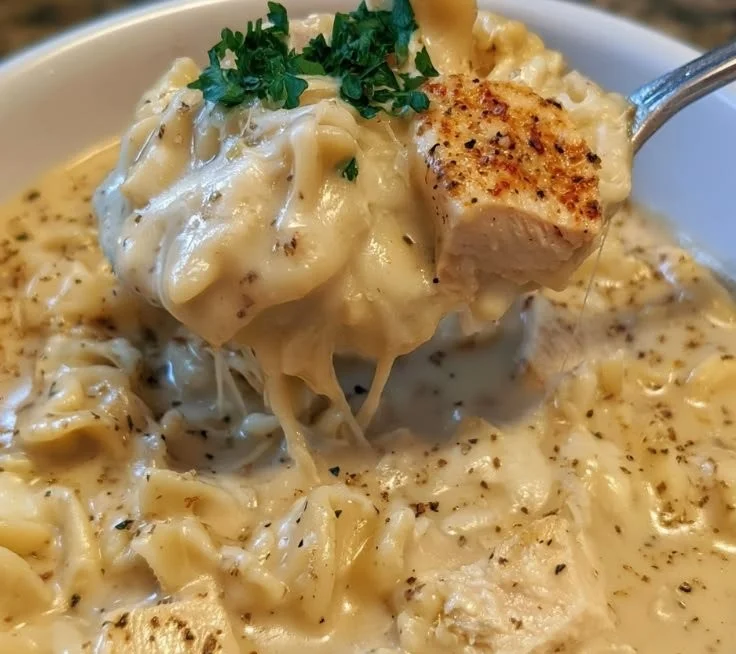 Bowl of creamy Chicken Alfredo Soup garnished with parsley and bread