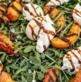 Grilled Peach Burrata Salad with Arugula served on a white plate