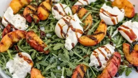 Grilled Peach Burrata Salad with Arugula served on a white plate