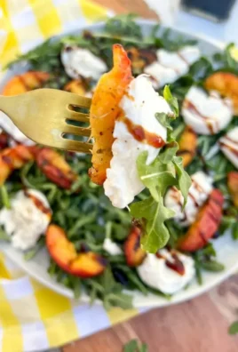 Grilled peach burrata salad with arugula and balsamic drizzle on a platter