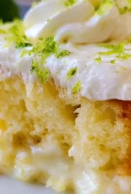 Slice of Key Lime Poke Cake with zesty lime topping and graham cracker crust