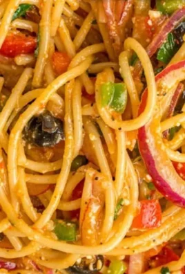 Colorful bowl of spaghetti salad with fresh vegetables and dressing