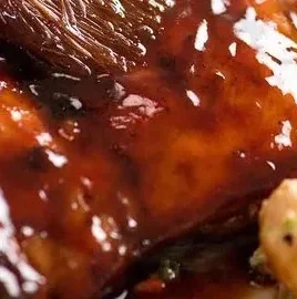 Succulent sticky grilled chicken on the barbecue, garnished with fresh herbs.