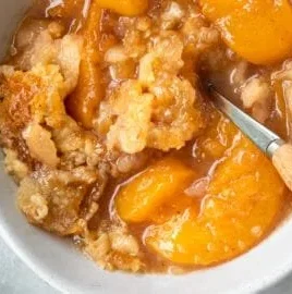 Delicious Southern peach cobbler served in a dish with fresh peaches.